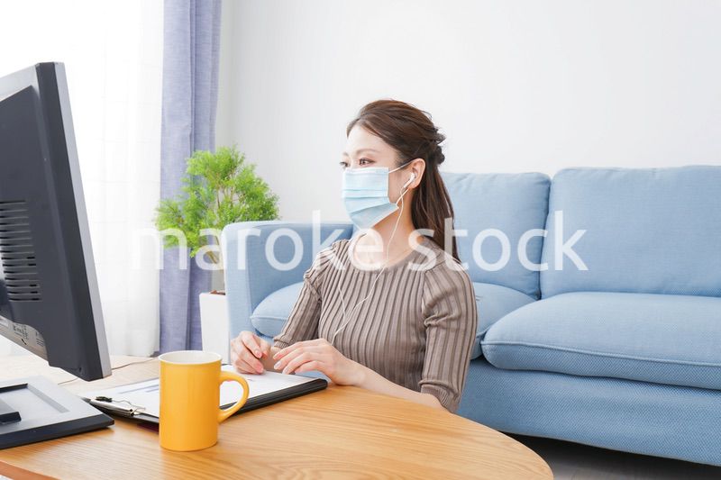マスクをしてオンライン会議に参加する若いビジネスウーマン