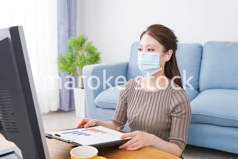 マスクをしてオンライン会議に参加する若いビジネスウーマン