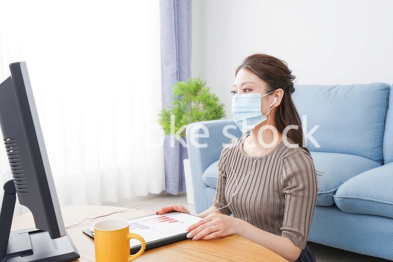 マスクをしてオンライン会議に参加する若いビジネスウーマン