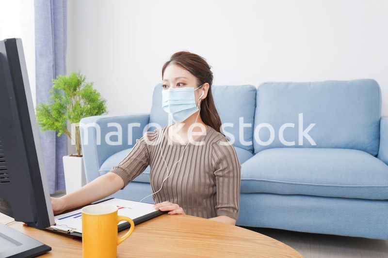 マスクをしてオンライン会議に参加する若いビジネスウーマン