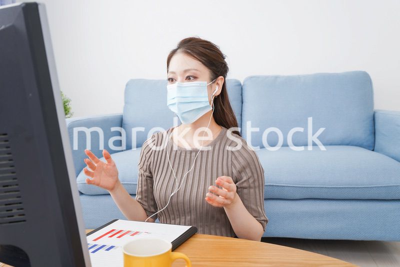 マスクをしてオンライン会議に参加する若いビジネスウーマン