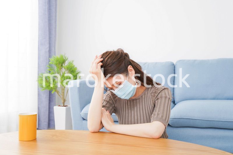 体調不良に苦しむマスクをつけた女性
