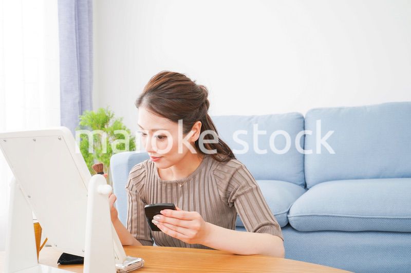 一人暮らしの部屋で化粧をする女性
