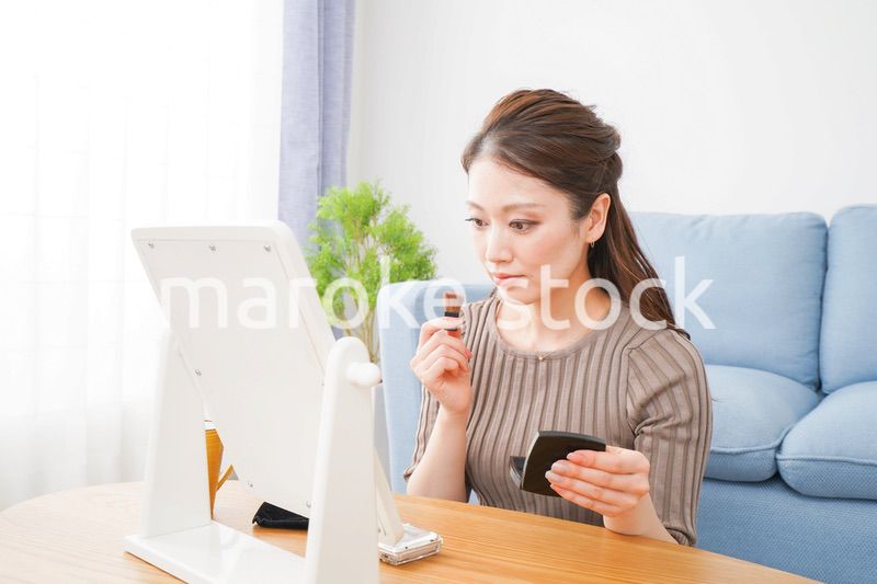 一人暮らしの部屋で化粧をする女性