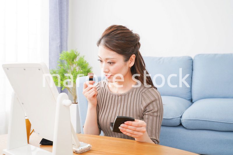 一人暮らしの部屋で化粧をする女性
