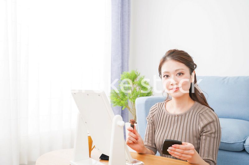 一人暮らしの部屋で化粧をする女性