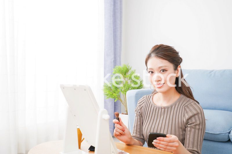 一人暮らしの部屋で化粧をする女性