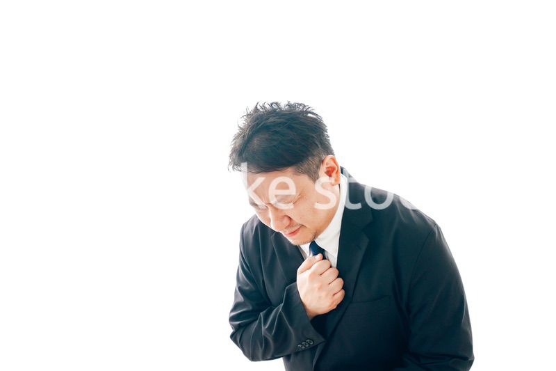 胸の痛みに苦しむスーツを着た中年男性