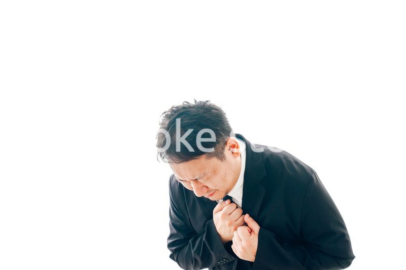 胸の痛みに苦しむスーツを着た中年男性