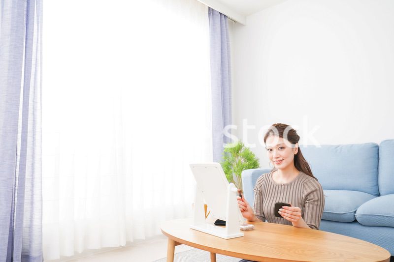一人暮らしの部屋で化粧をする女性