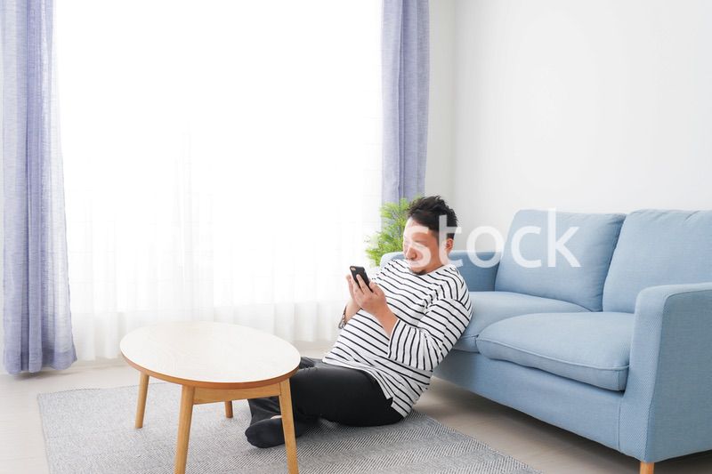 部屋でスマホを使う男性