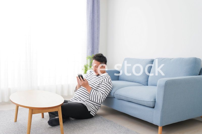 部屋でスマホを使う男性
