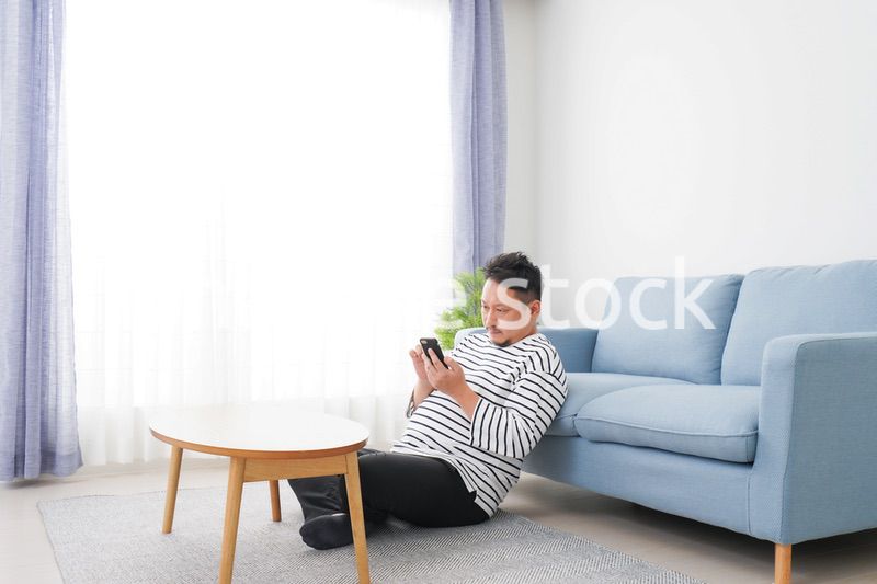 部屋でスマホを使う男性