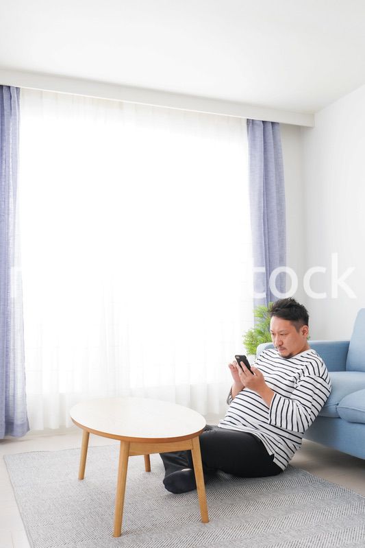 部屋でスマホを使う男性