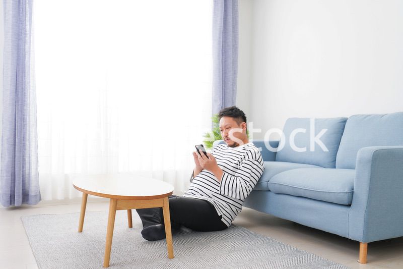 部屋でスマホを使う男性
