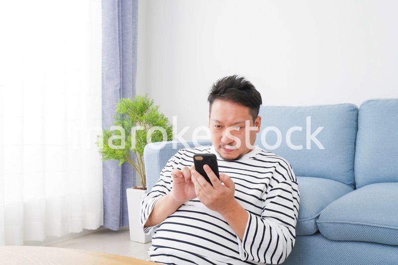 部屋でスマホを使う男性