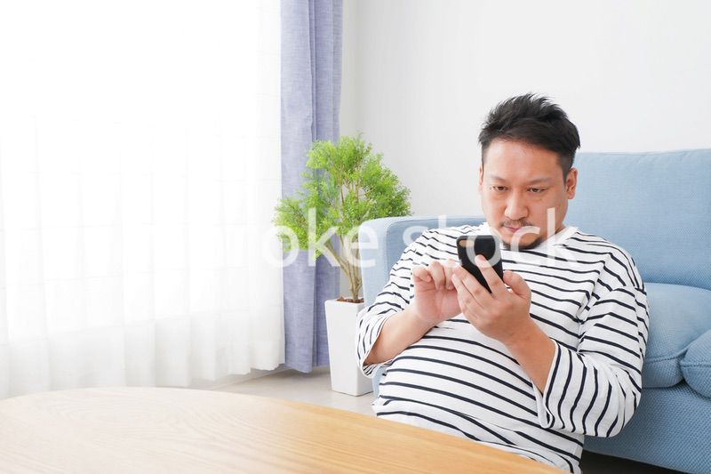 部屋でスマホを使う男性