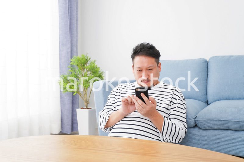 部屋でスマホを使う男性