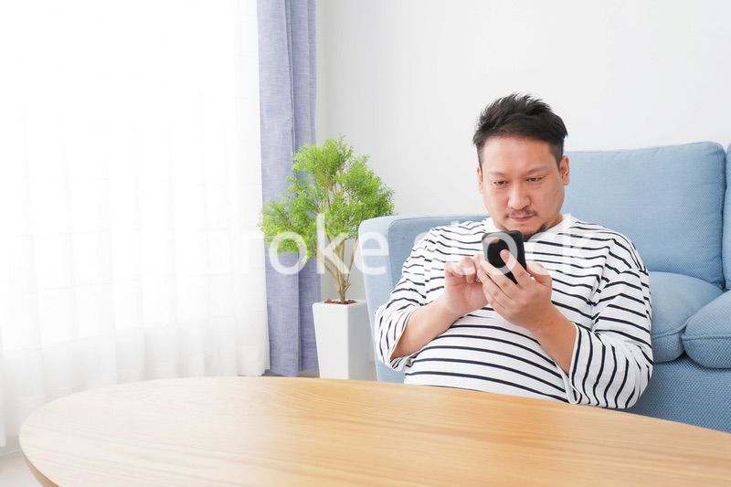 部屋でスマホを使う男性