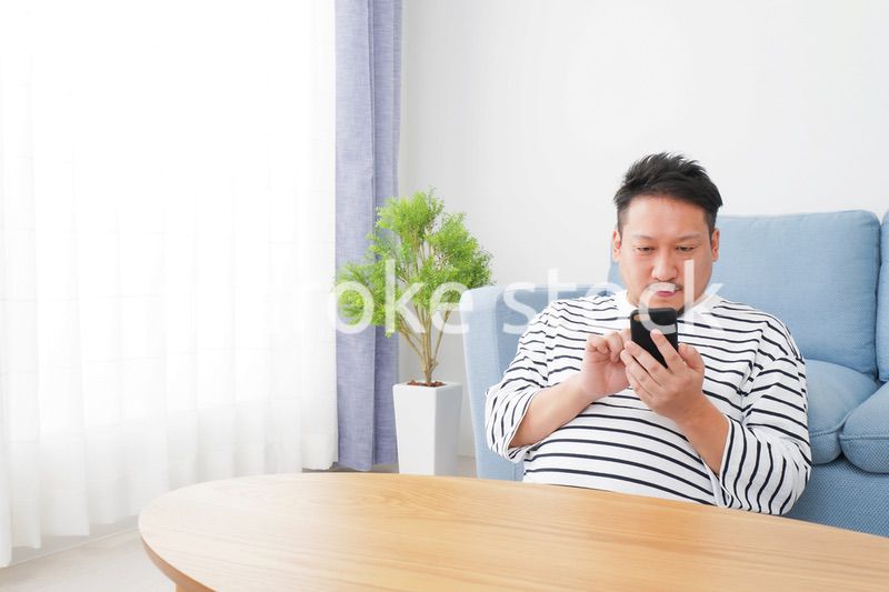 部屋でスマホを使う男性