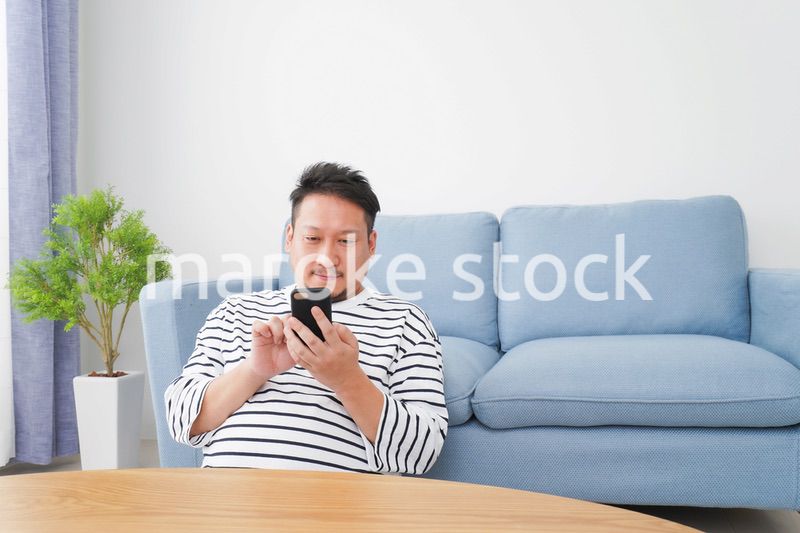 部屋でスマホを使う男性