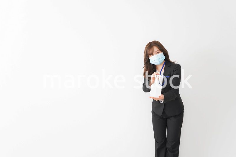 アルコール消毒液を差し出すビジネスウーマン