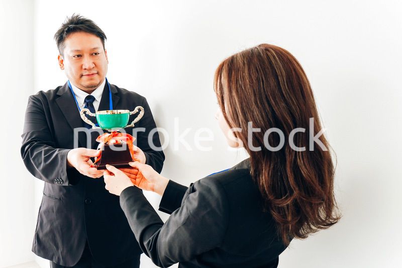 社内表彰で上司からトロフィーをもらうビジネスウーマン