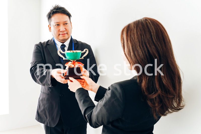 社内表彰で上司からトロフィーをもらうビジネスウーマン