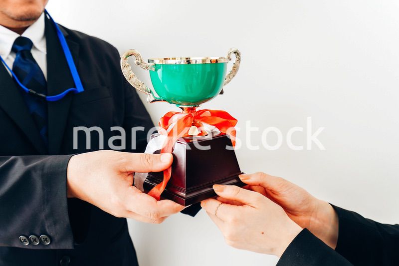 社内表彰で上司からトロフィーをもらうビジネスウーマン