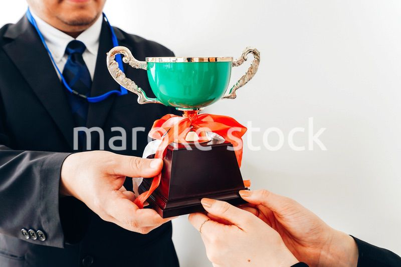 社内表彰で上司からトロフィーをもらうビジネスウーマン