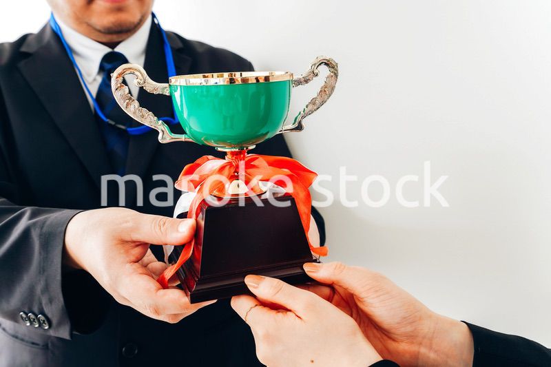 社内表彰で上司からトロフィーをもらうビジネスウーマン