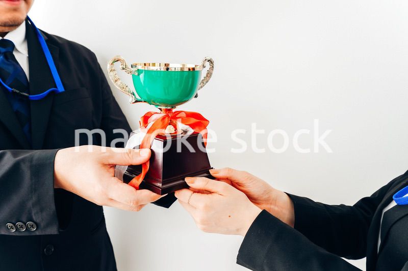 社内表彰で上司からトロフィーをもらうビジネスウーマン