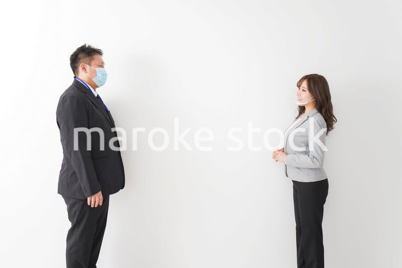 ソーシャルディスタンスを確保し、オフィスで会話をするビジネスパーソン