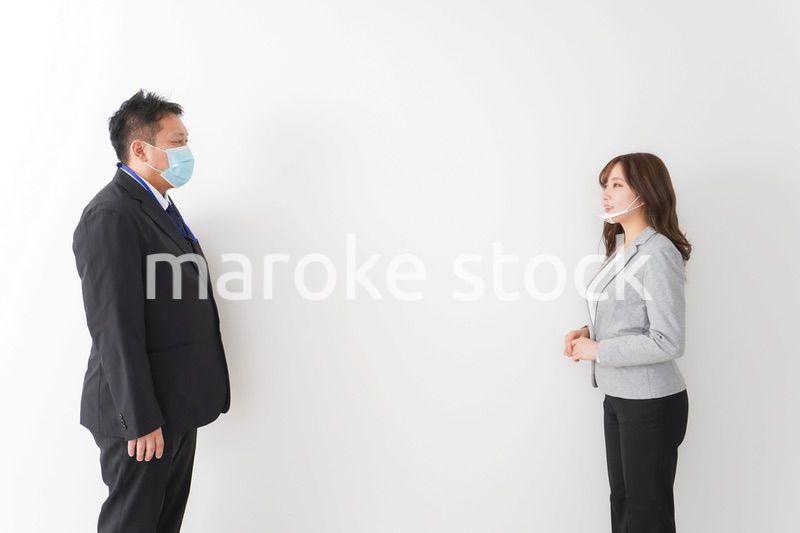 ソーシャルディスタンスを確保し、オフィスで会話をするビジネスパーソン