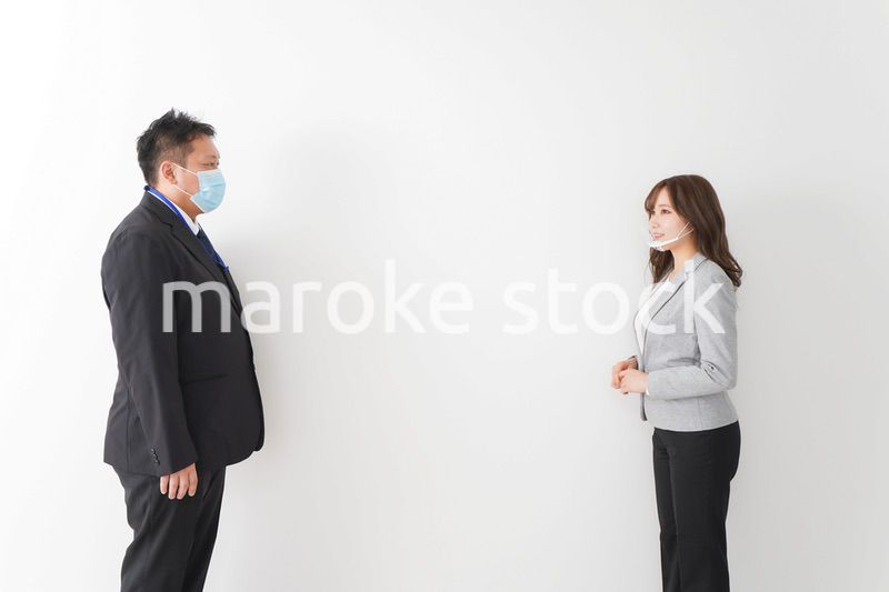 ソーシャルディスタンスを確保し、オフィスで会話をするビジネスパーソン