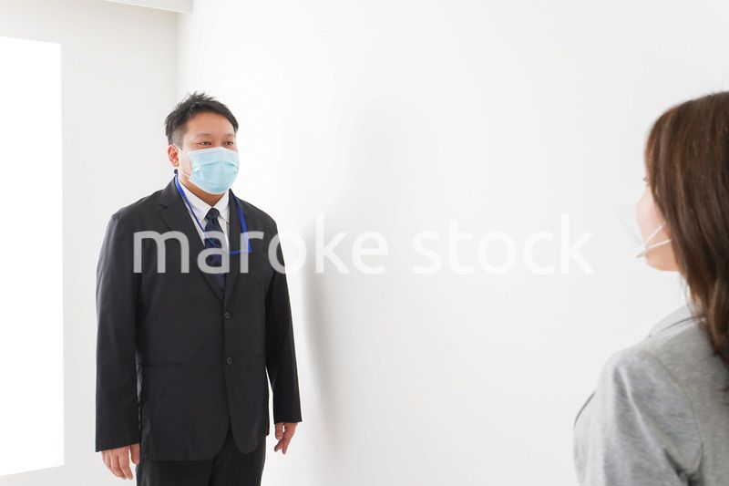 ソーシャルディスタンスを確保し、オフィスで会話をするビジネスパーソン