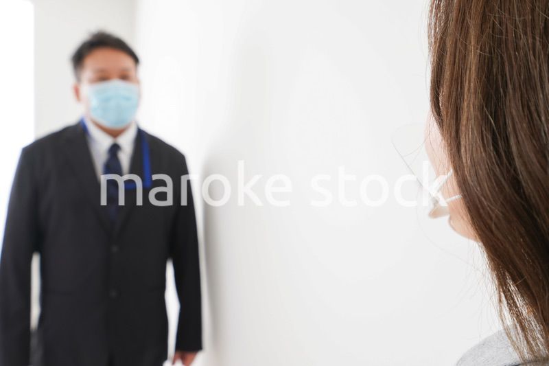 ソーシャルディスタンスを確保し、オフィスで会話をするビジネスパーソン