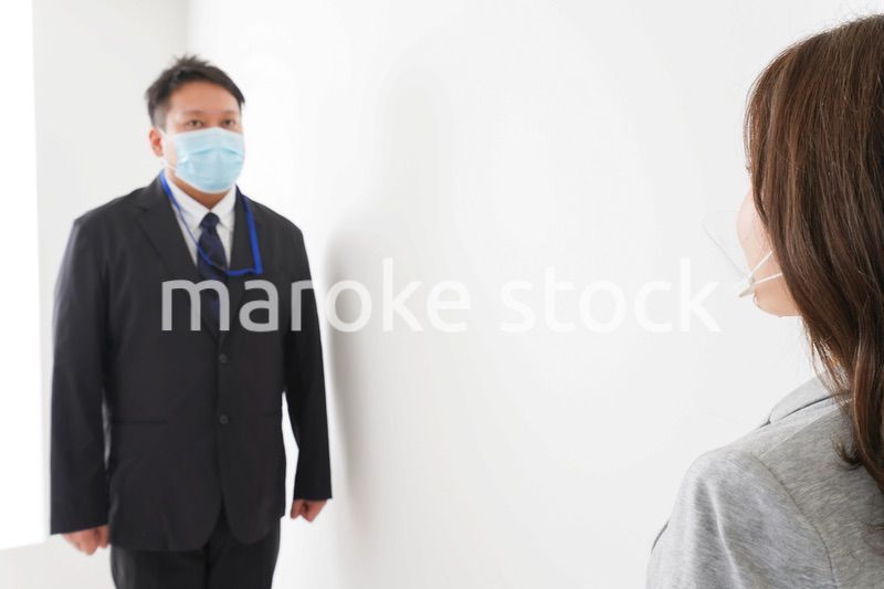 ソーシャルディスタンスを確保し、オフィスで会話をするビジネスパーソン