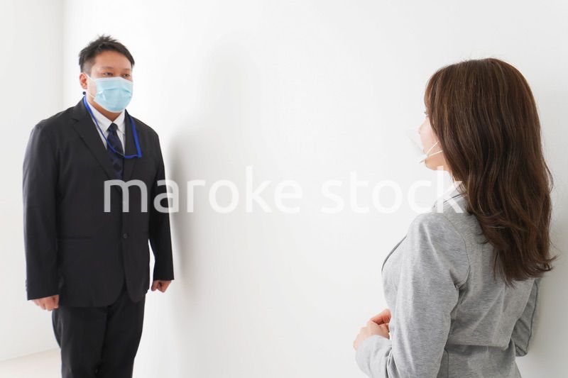 ソーシャルディスタンスを確保し、オフィスで会話をするビジネスパーソン