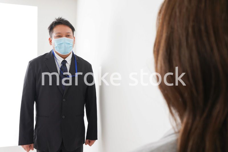 ソーシャルディスタンスを確保し、オフィスで会話をするビジネスパーソン