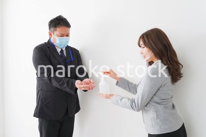 アルコール消毒をお願いするビジネスパーソン
