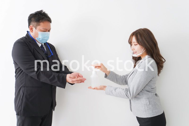 アルコール消毒をお願いするビジネスパーソン