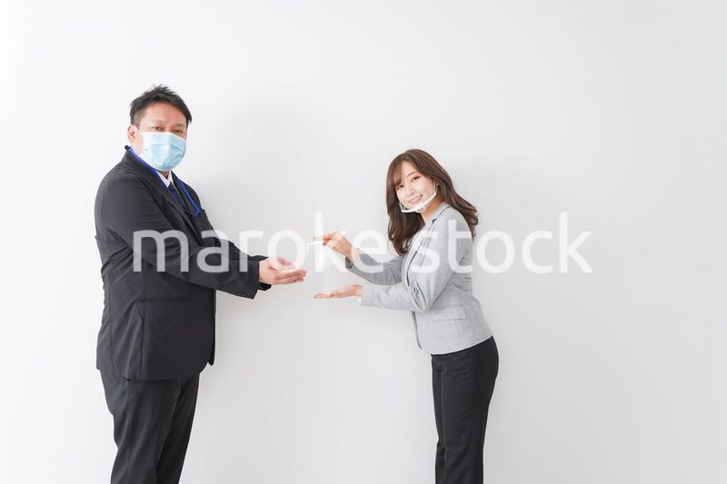 アルコール消毒をお願いするビジネスパーソン