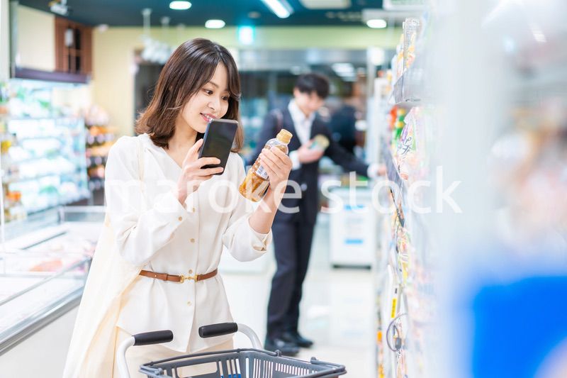 スーパーの商品をスマホで調べる若い女性