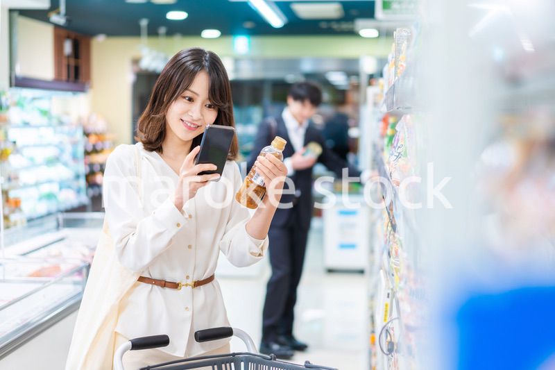 スーパーの商品をスマホで調べる若い女性