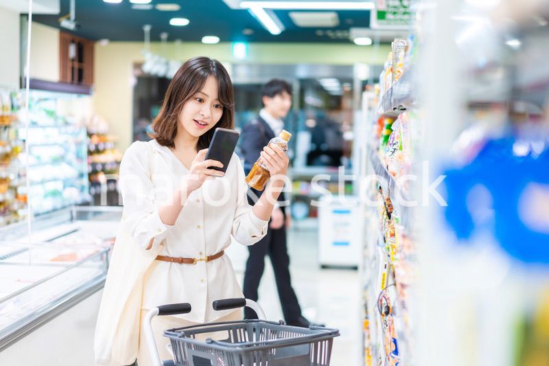 スーパーの商品をスマホで調べる若い女性