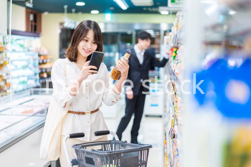 スーパーの商品をスマホで調べる若い女性