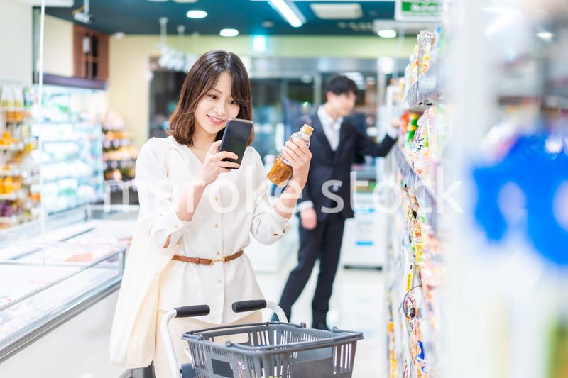 スーパーの商品をスマホで調べる若い女性