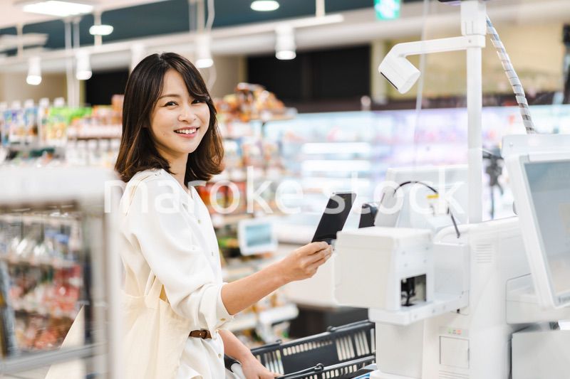 スーパーでスマホ決済を使う若い女性