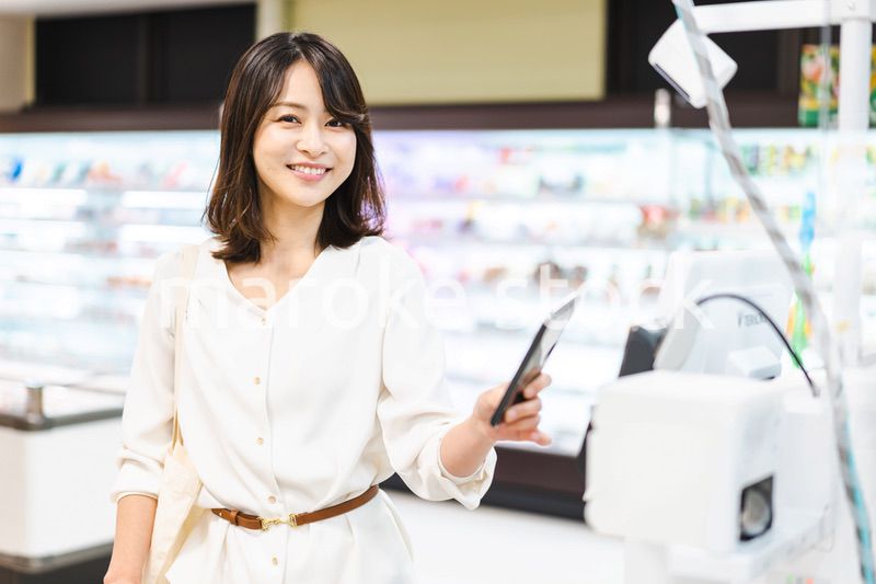 スーパーでスマホ決済を使う若い女性